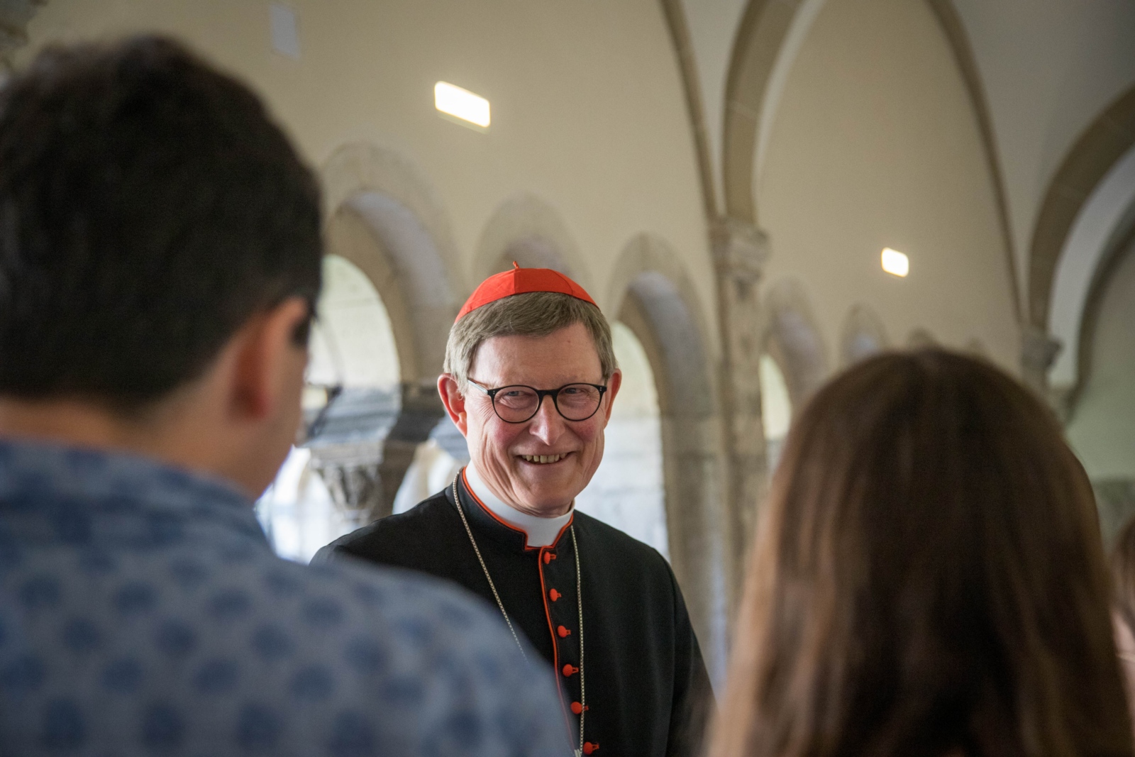 Kardinal Woelki im Gespräch mit jungen Menschen im Kreuzgang des Bonner Münsters